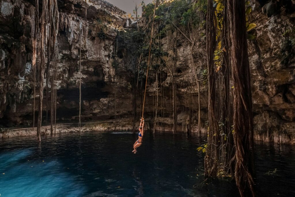 a woman from a rope into a cenote