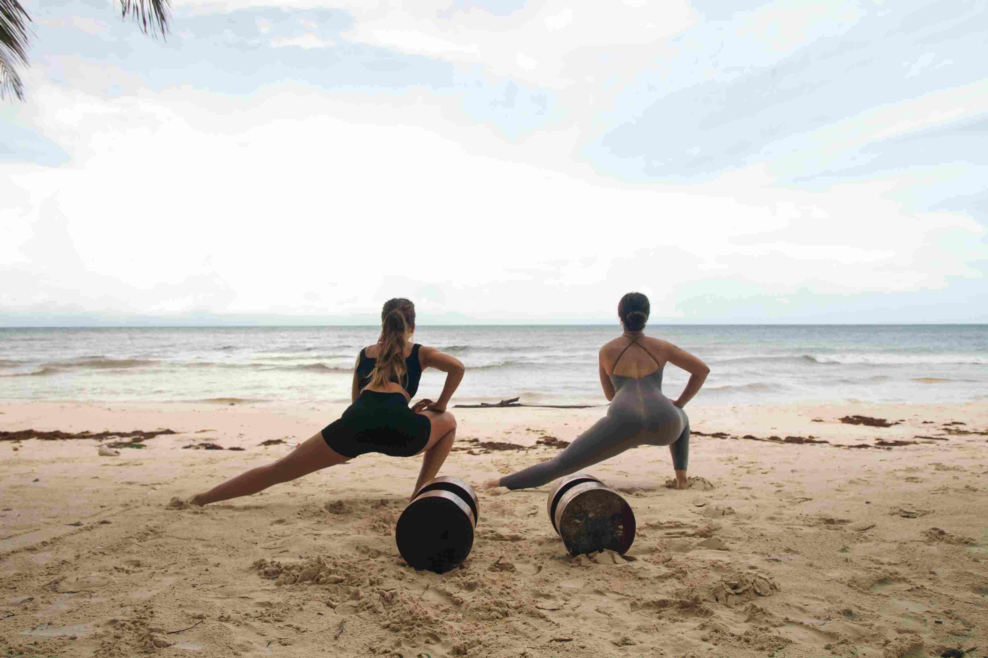 two girls doing yoga at the beach