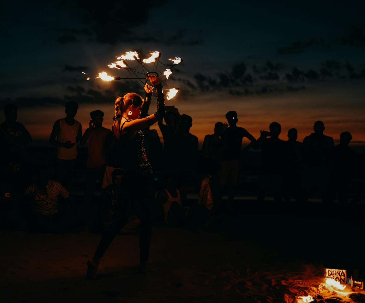 A mesmerizing fire dancer entertains a crowd at sunset on Arambol Beach, India.