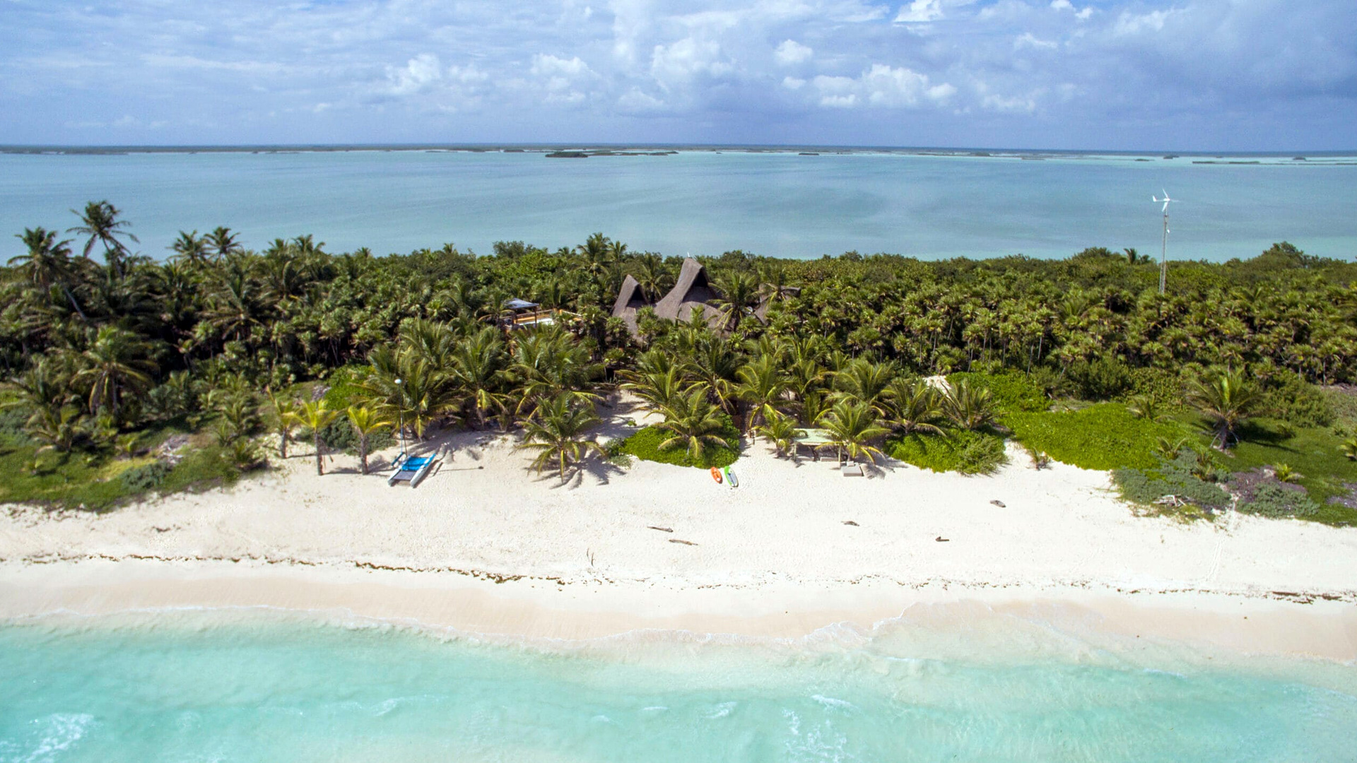 Aerial view of the white-sand beach and palm jungle in front of Casa Nalum in Sian Ka'an, with the lagoon behind