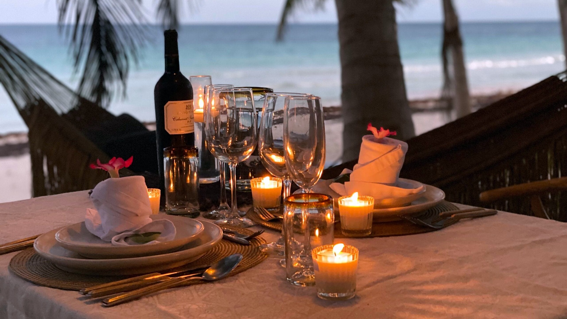 A candlelit table set on the beach at Casa Nalum at dusk