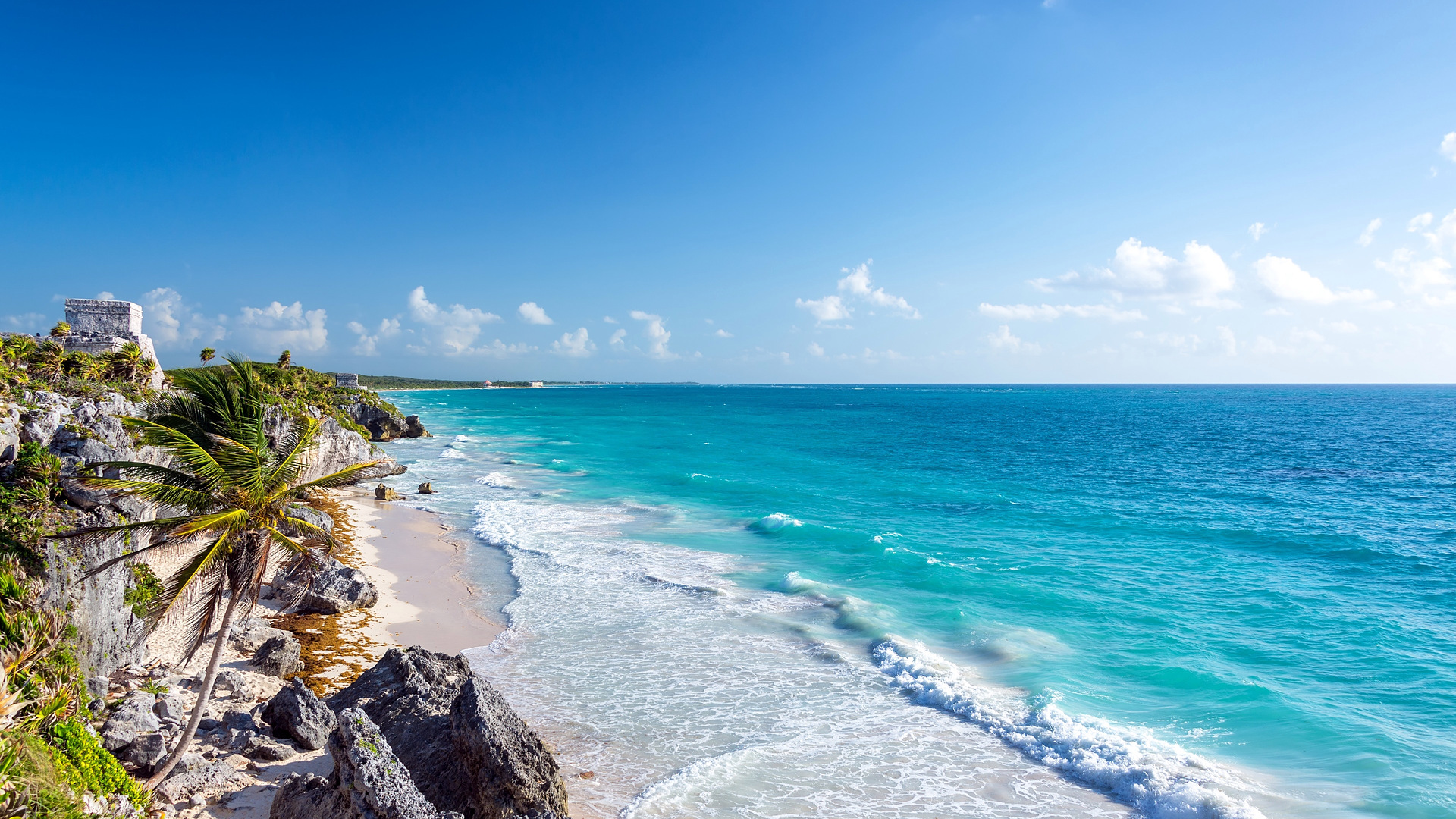 The Tulum ruins on the cliff above a turquoise beach on the Caribbean coast of Tulum