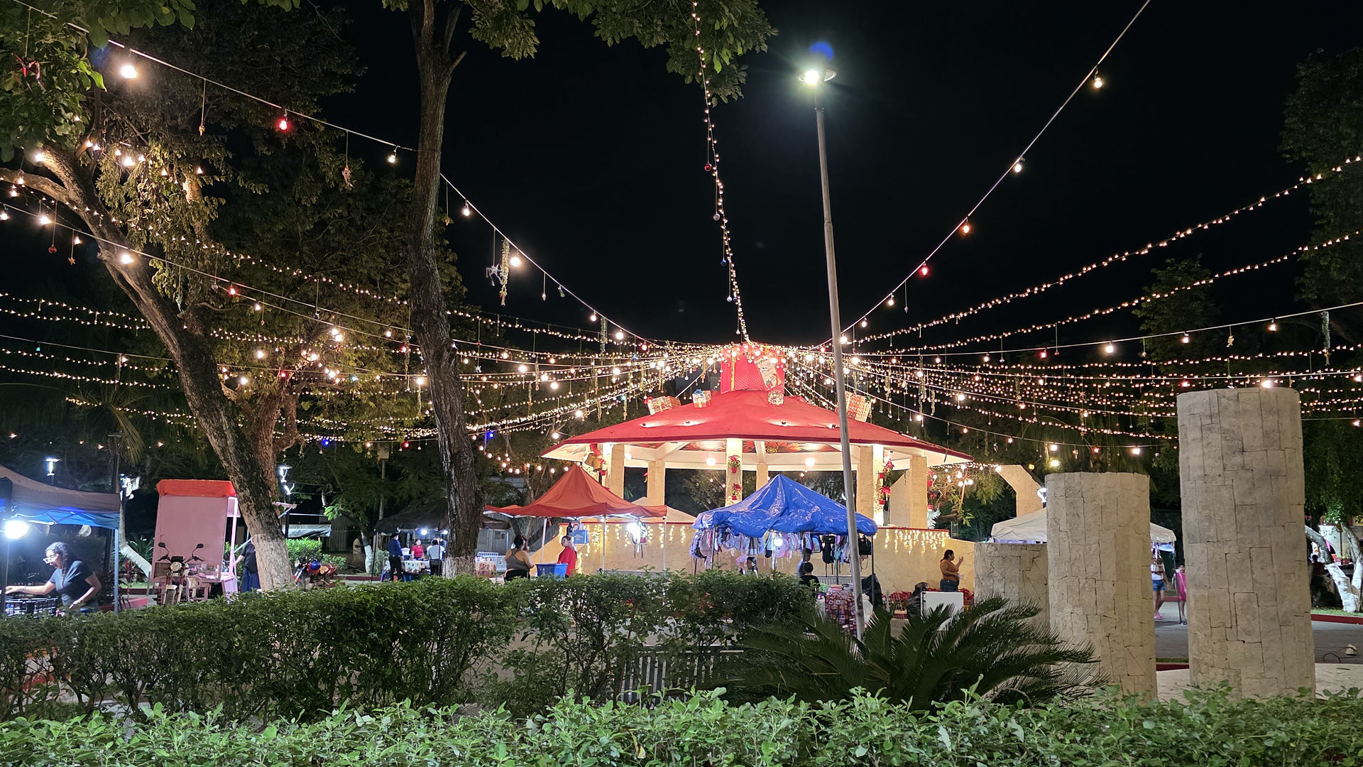 String lights and a lit kiosk at night during the holidays in Parque Dos Aguas, Tulum's main square